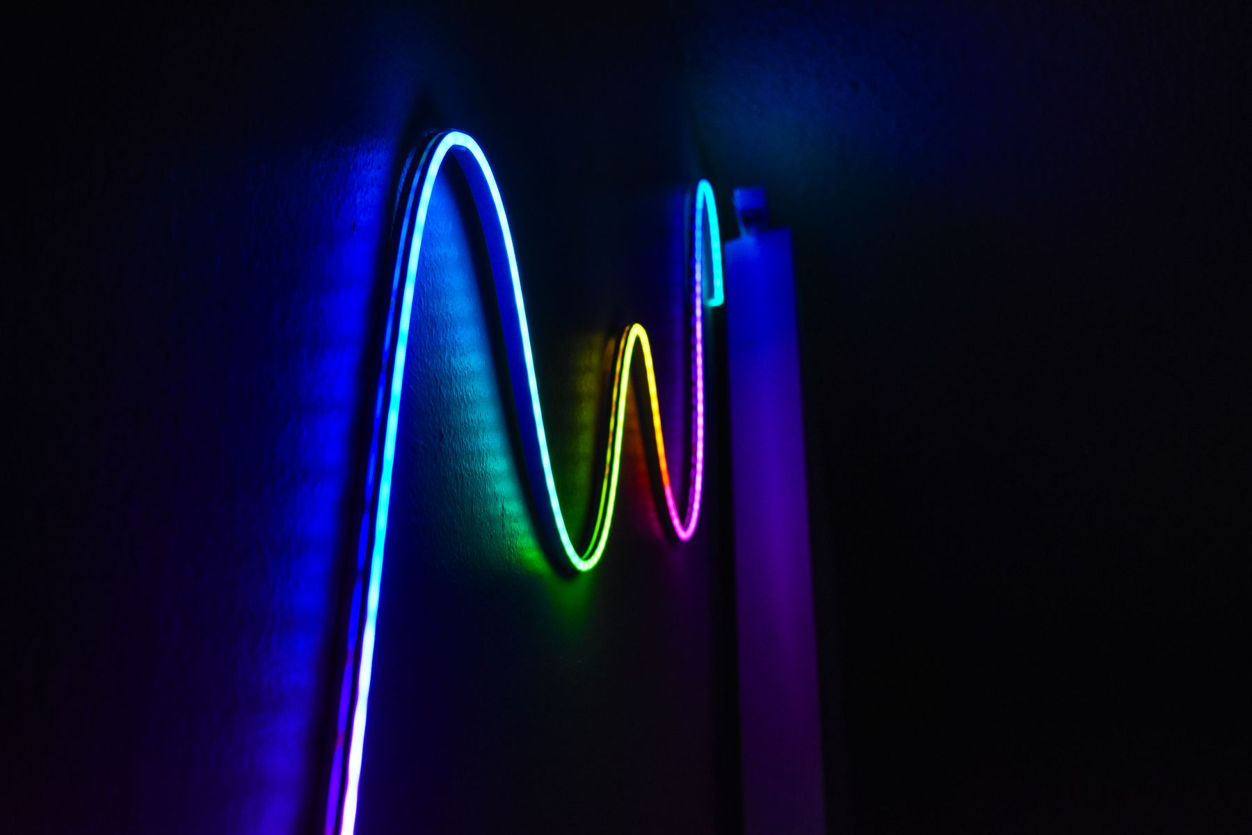 A coloured LED light strip mounted on a dark wall