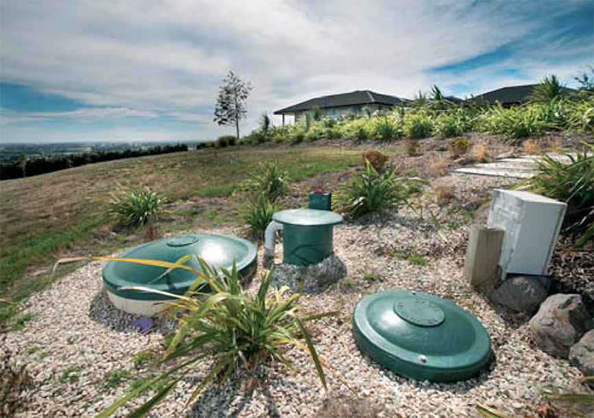 Green wastewater tank lids and a control box on a rural section